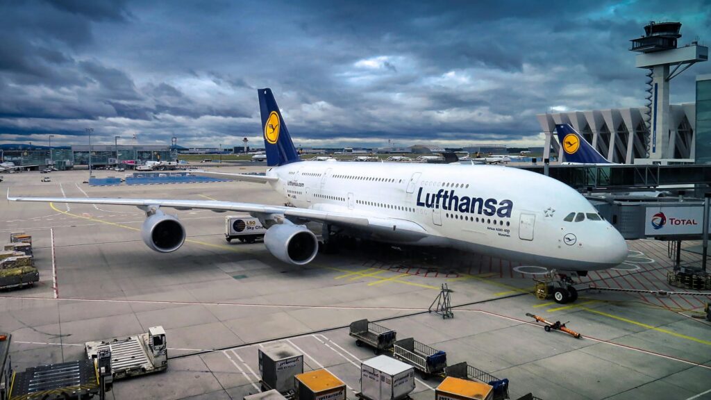 pexels-photo-358220-358220 Lufthansa Airbus A380 parked at the airport gate, ready for departure under a dramatic cloudy sky.